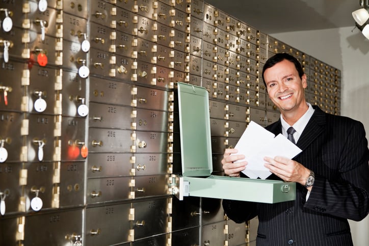 A person stores an important document in a bank locker.