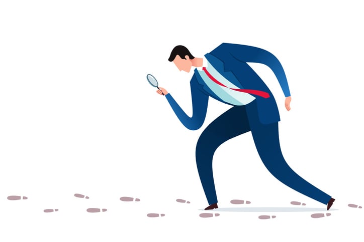 man with magnifying glass following trail