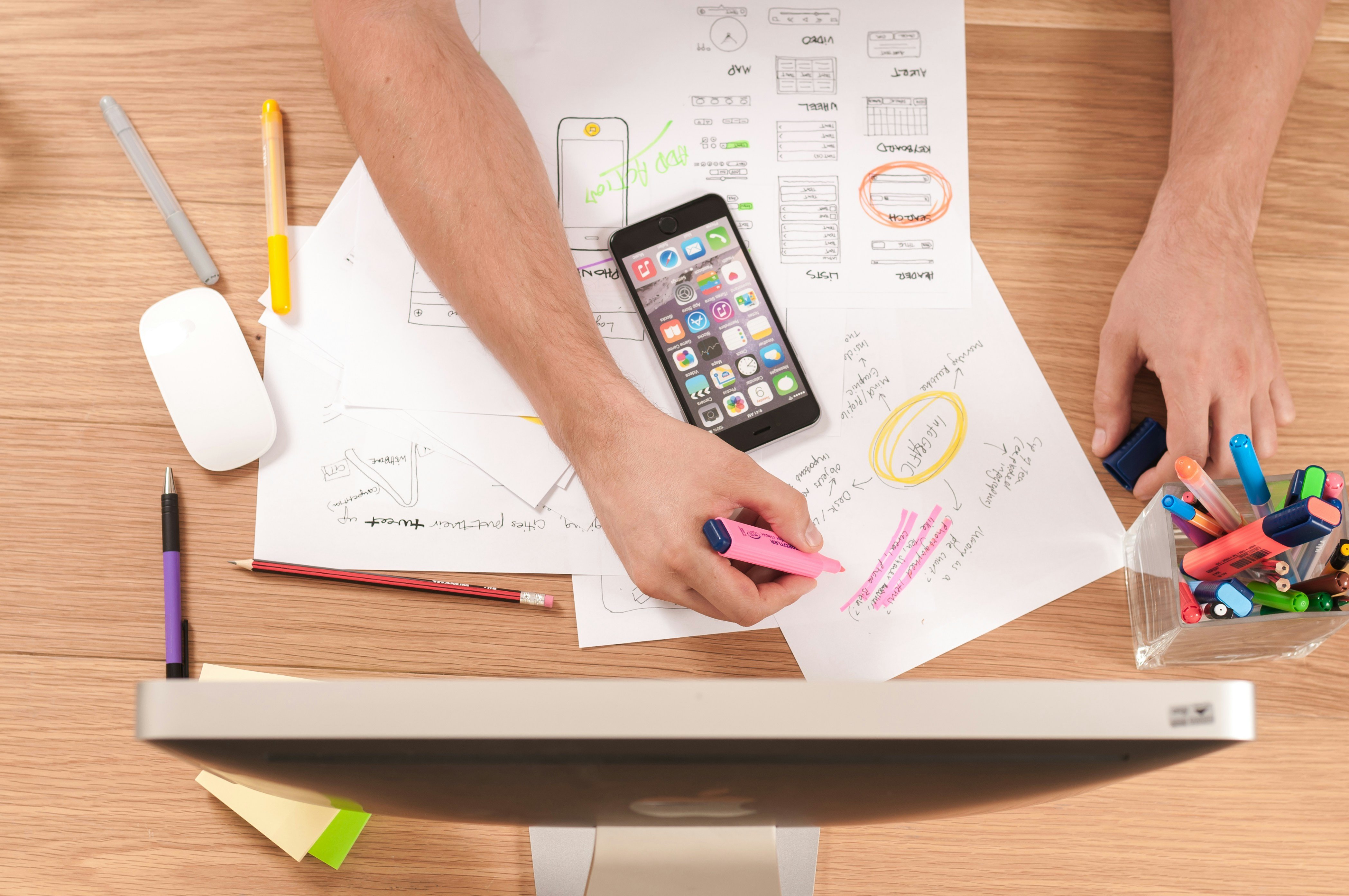 Image of someone working on notes, a smartphone, and a computer