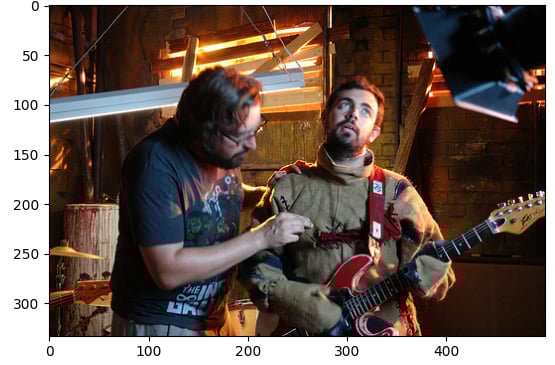 Photo of 2 people, 1 is playing the guitar